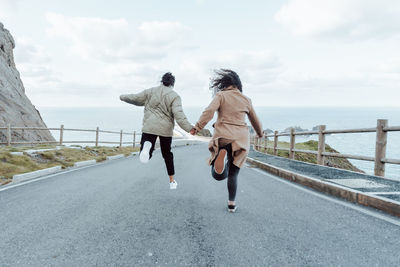 Rear view of woman walking on road against sky