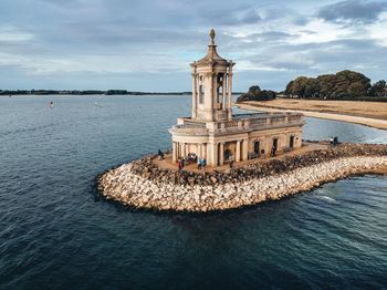 View of building by sea against cloudy sky