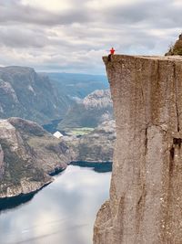 Low angle view of man sitting on cliff against sky