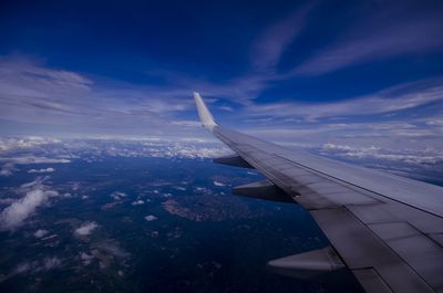 Airplane flying over landscape against blue sky