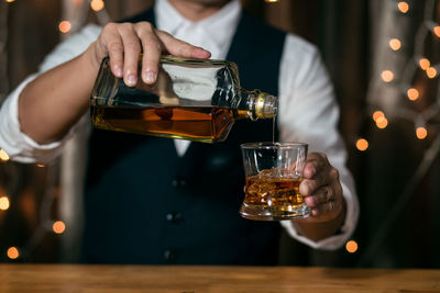 Midsection of man pouring wine in glass on table