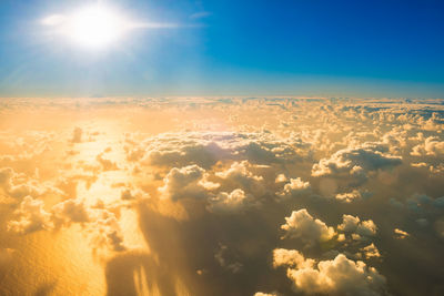 Airplane view of beautiful landscape with gold colored clouds, ocean and bright sunset shining sun