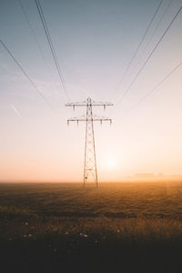 Electricity pylon on field against sky during sunset