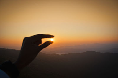 Optical illusion of cropped hand holding sun during sunset