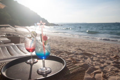 Wine glass on table at beach against sky