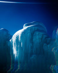 Snow covered rock formation against clear blue sky