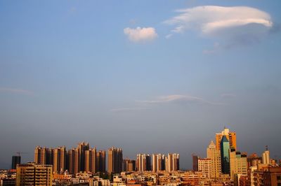 City at waterfront against cloudy sky