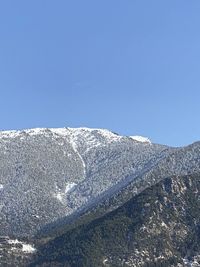 Low angle view of snowcapped mountain against clear blue sky