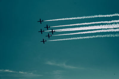 Low angle view of airshow in blue sky