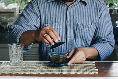 Midsection of man holding coffee cup on table