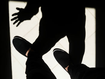 Low section of silhouette man against shadow