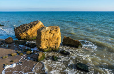 Scenic view of rocks on beach against sky