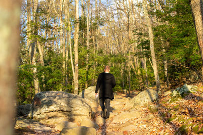 A young caucasian man wearing all black walking up a mountain path person