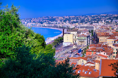 High angle view of townscape by sea against blue sky