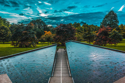 Footpath by swimming pool against sky during autumn