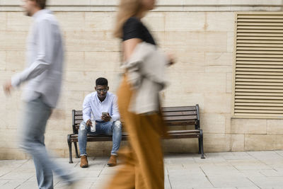 Young man with water bottle using smart phone on bench