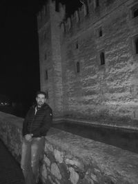 Portrait of young woman standing against building at night