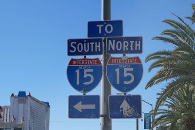 Low angle view of road sign against clear blue sky