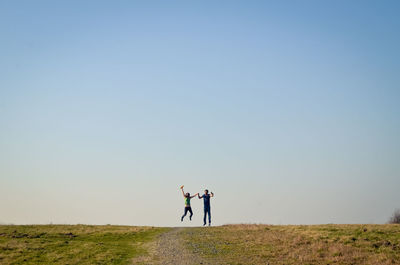 People standing on field against clear sky