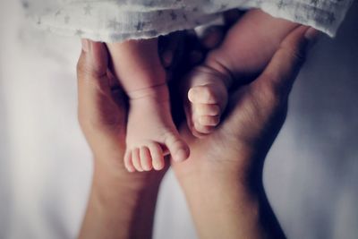 Low section of father holding newborn baby legs