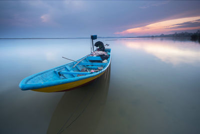 Boat moored on sea against sky during sunset