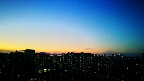 Illuminated buildings in city against sky during sunset