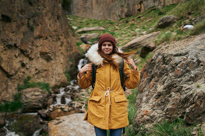 Portrait of young woman standing against rock