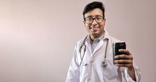 Portrait of smiling young man standing against wall