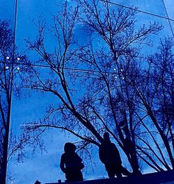 Silhouette people by bare tree against sky during winter