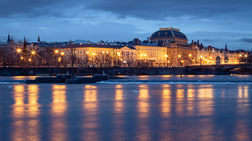 View of illuminated historic buildings along vltava river waterfront in prague, czech republic 