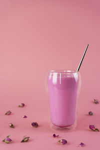 Pink rose milk with rose petals in a double walled glass. healthy drink moon milk. vertical.