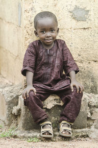 Portrait of boy sitting against wall