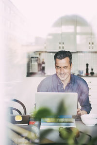 Happy man having video call in kitchen working at home