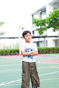 Boy standing with arms crossed at basketball court