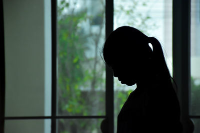 Close-up portrait of silhouette man standing against window at home