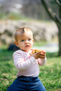Baby girl holding foods outdoors