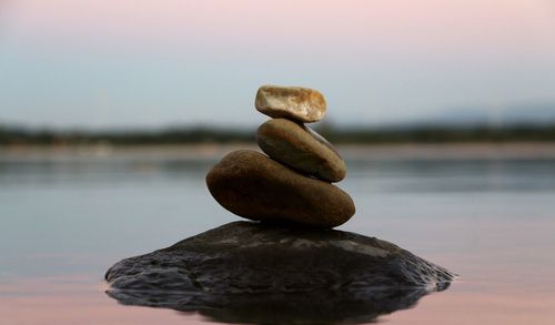 Close-up of pebbles on beach against sky during sunset