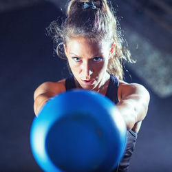 Portrait of female athlete exercising with kettlebell in gym