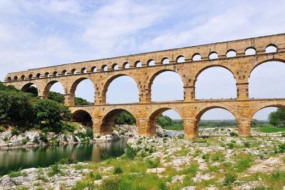 Low angle view of arch bridge over river against sky