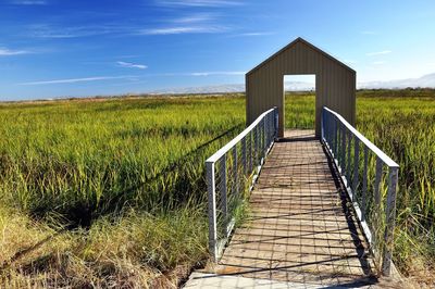 Wooden structure on field against sky