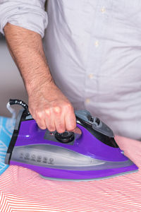 Midsection of man ironing textile on board