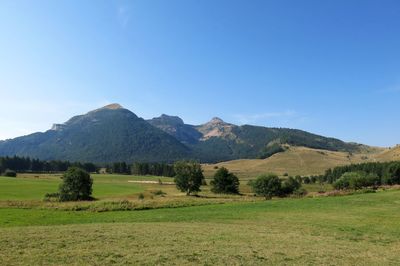 Scenic view of landscape and mountains against clear blue sky