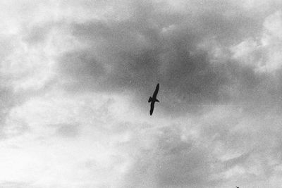 Low angle view of airplane flying against cloudy sky