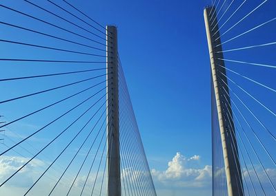 Low angle view of suspension bridge against blue sky