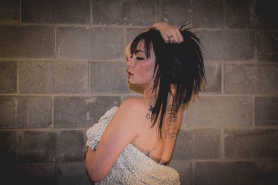 Beautiful young woman standing against brick wall