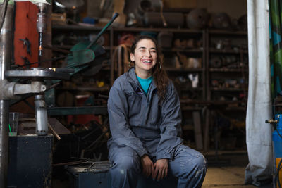 Happy mid adult woman sitting in workshop