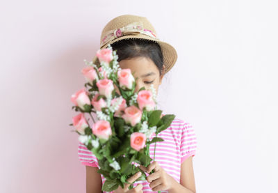 Low angle view of girl holding bouquet against white background