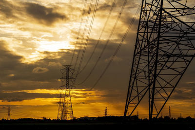 Low angle view of silhouette electricity pylon against sky during sunset