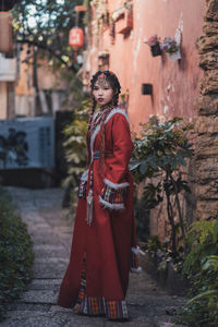 Portrait of young woman standing against trees