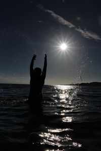 Rear view of silhouette woman in sea against sky